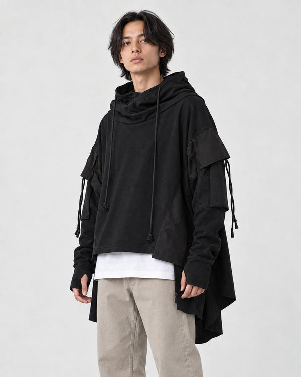 Model wearing the black layered sleeve hoodie with the hood down, stone trousers and white sneakers, three-quarter view