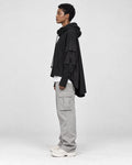 Model wearing the black layered sleeve hoodie in profile, showing the long cape panel at the back