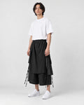 Model wearing the black layered wrap pants, three-quarter view