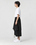 Model wearing the black layered pants, side view of the wrap panel and ties