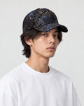 Model wearing the dark navy foil leaf print baseball cap with a white tee, three-quarter view