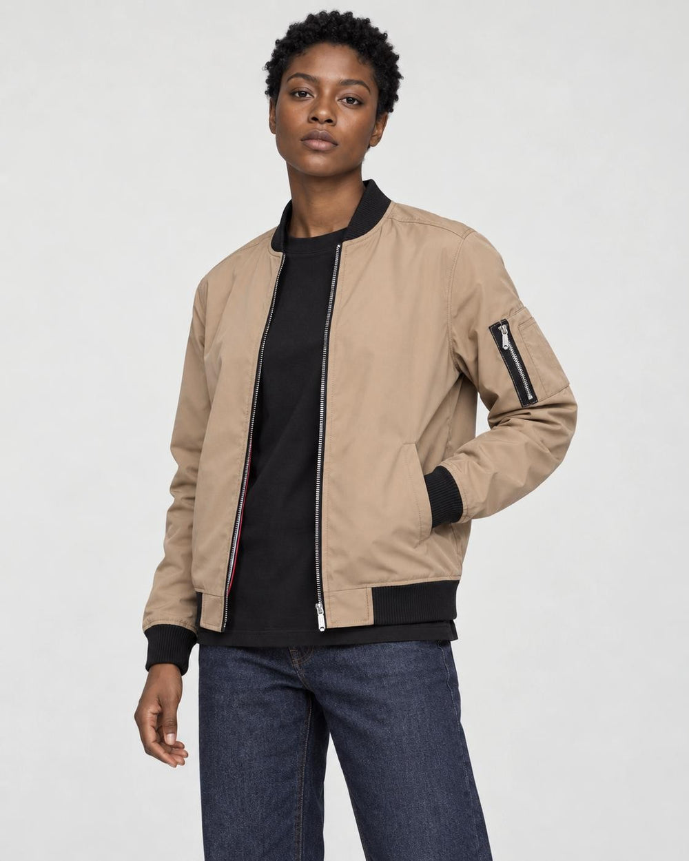 Model wearing the khaki bomber jacket open over a black tee, three-quarter view