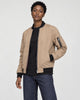 Model wearing the khaki bomber jacket open over a black tee, three-quarter view