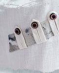 Close-up of the slanted row of buttoned tabs stitched over an ink-print strip
