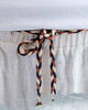 Close-up of the gathered elastic waist and the braided cord knotted at the front