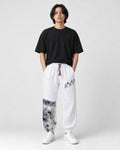 Model wearing the white linen-cotton jogger pants with a black tee and white sneakers, front view