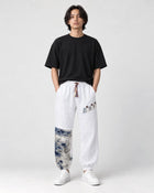 Model wearing the white linen-cotton jogger pants with a black tee and white sneakers, front view