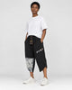 Model wearing the black linen drop-crotch pants with a white tee and white sneakers, three-quarter view
