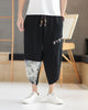 Black linen drop-crotch pants with a toggle patch row on the thigh and an ink-wash print panel on the lower leg