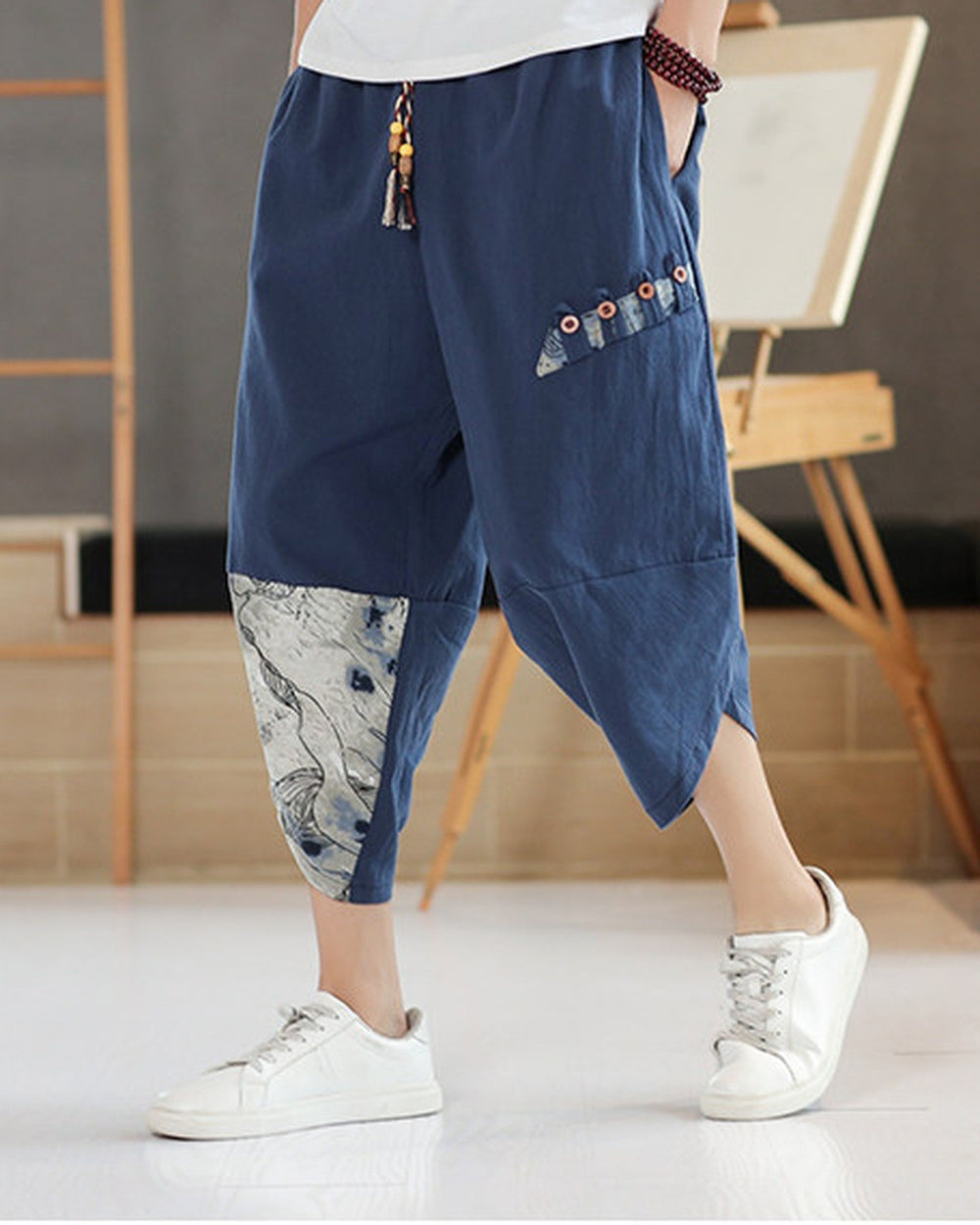 Navy linen drop-crotch pants with a toggle patch row on the thigh and an ink-wash print panel on the lower leg