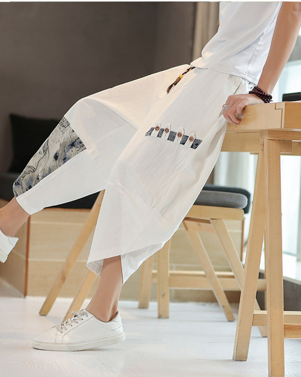 Side view of the white linen pants showing the toggle patch row on the thigh and the cut-away hem