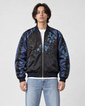 Model wearing the black and navy lion souvenir jacket half zipped, front view