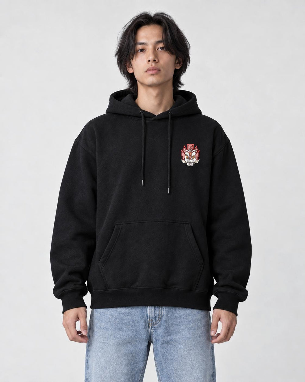 Model wearing the black hoodie with the small lion emblem on the chest, front view