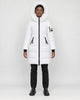 Model wearing the white long puffer coat with a white faux-fur hood, black jeans and black boots, front view