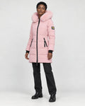 Model wearing the pink long puffer coat with a pink faux-fur hood, black jeans and black boots, three-quarter view