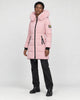 Model wearing the pink long puffer coat with a pink faux-fur hood, black jeans and black boots, three-quarter view