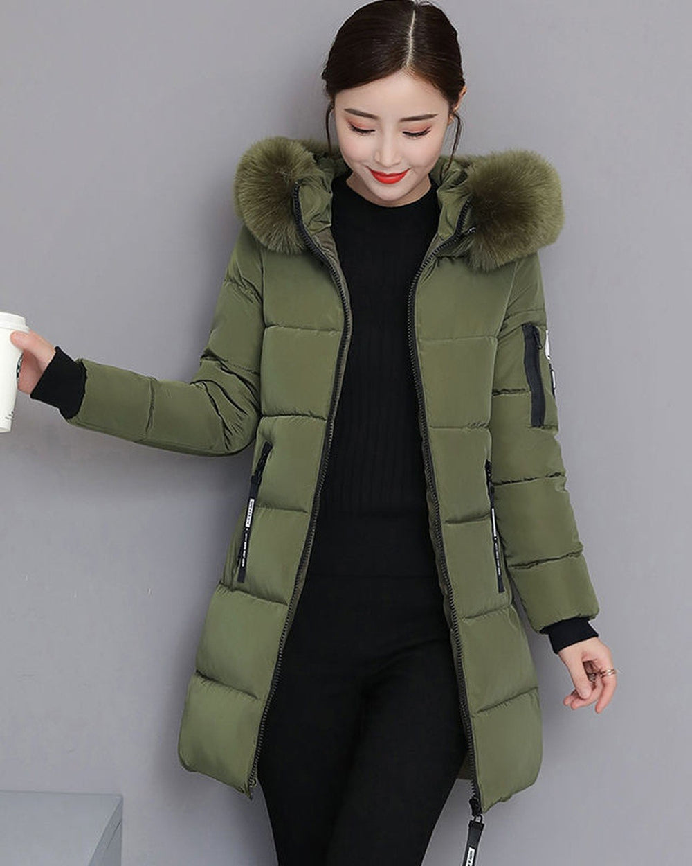 Army green long puffer coat with an olive faux-fur collar and black knit cuffs, worn with black pants
