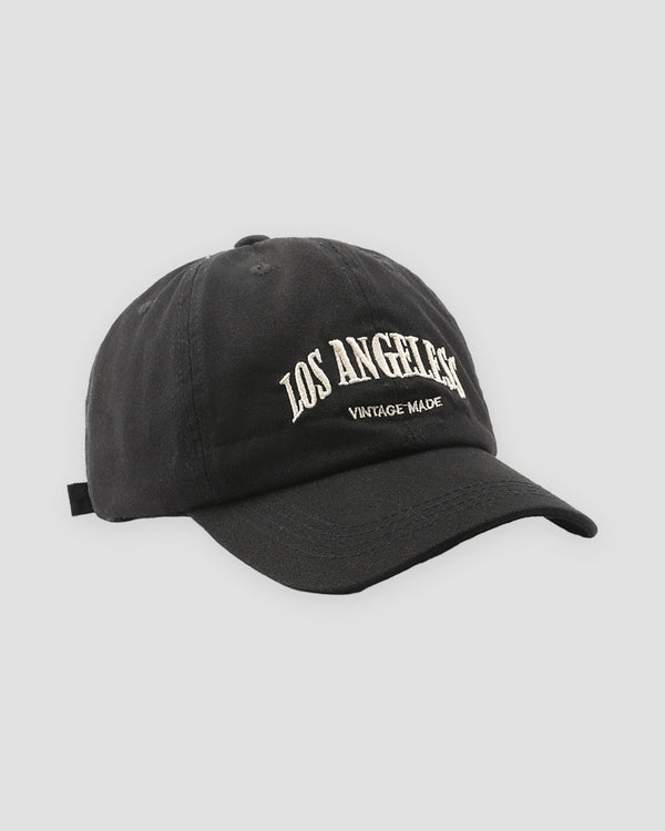 Black Los Angeles dad cap, three-quarter view, off-white arched lettering