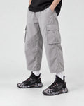Model wearing the black marble print high-top sneakers with light gray cargo trousers, front view