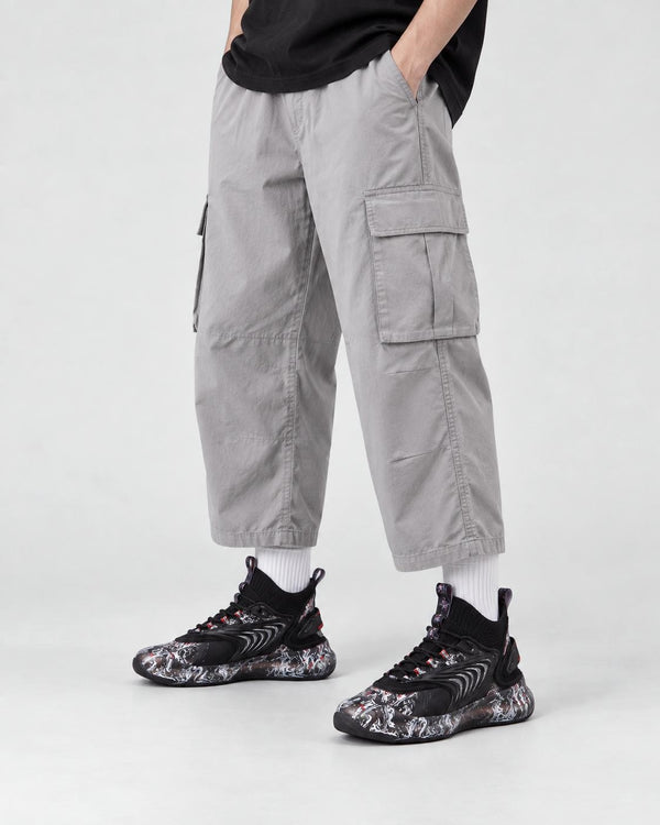 Model wearing the black marble print high-top sneakers with light gray cargo trousers, front view