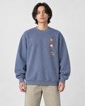 Model wearing the dusty blue crewneck sweatshirt with three small space icons on the chest, with stone trousers