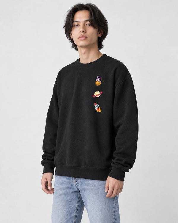 Model wearing the black crewneck sweatshirt with three small space icons, with light-wash jeans, three-quarter view