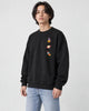 Model wearing the black crewneck sweatshirt with three small space icons, with light-wash jeans, three-quarter view