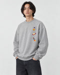 Model wearing the heather gray crewneck sweatshirt with three small space icons on the chest, with dark jeans