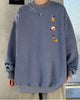 Dusty blue crewneck sweatshirt with an astronaut, a ringed planet and a rocket printed in a column on the left chest