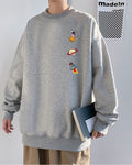 Heather gray crewneck sweatshirt with an astronaut, a ringed planet and a rocket printed in a column on the left chest