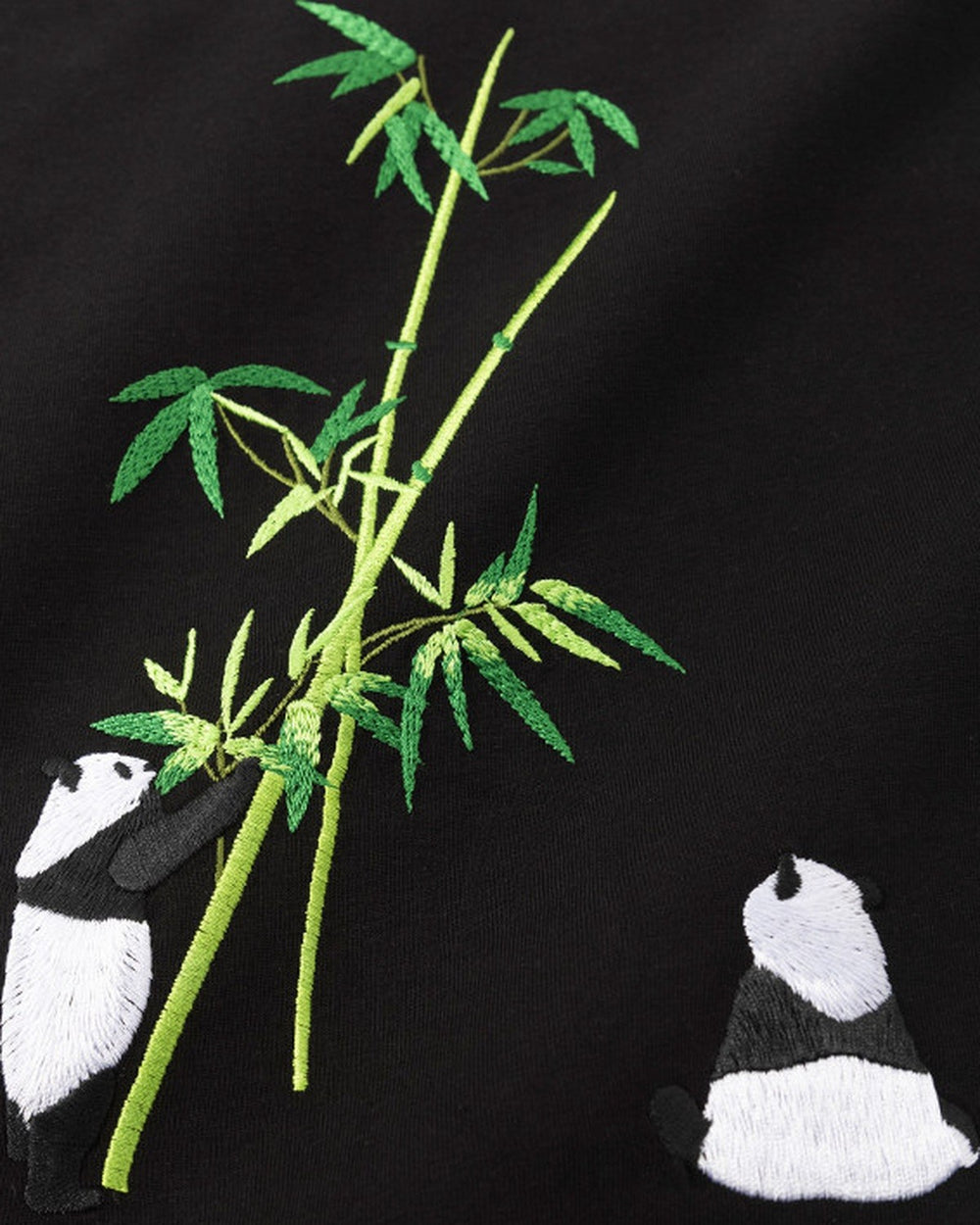 Close-up of the lower back embroidery on the black T-shirt: a bamboo stalk with two pandas