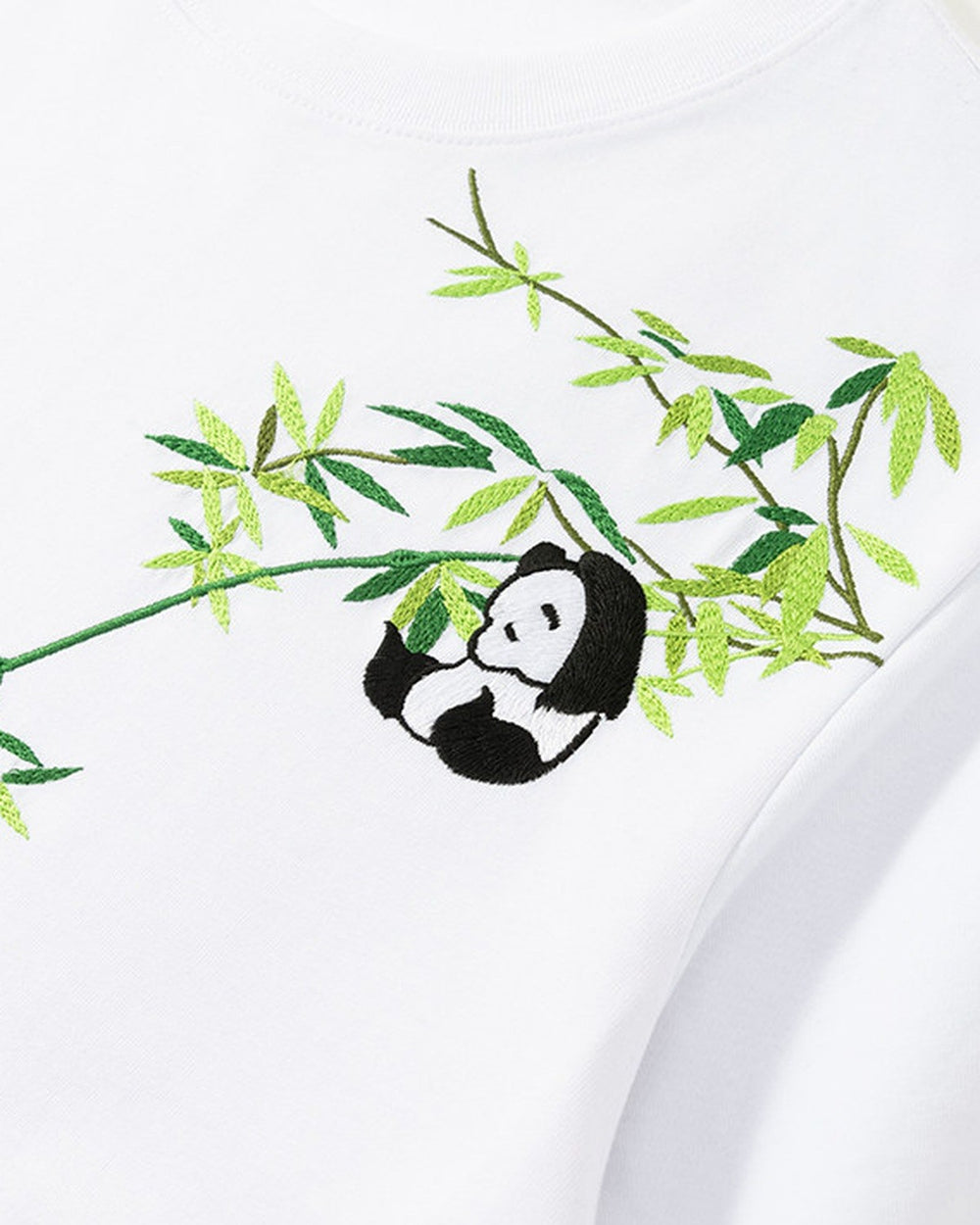 Close-up of the bamboo sprig and panda embroidered on the shoulder and chest of the white T-shirt