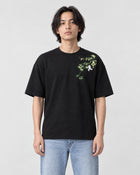 Model wearing the black bamboo and panda embroidered T-shirt with light jeans and white sneakers, front view