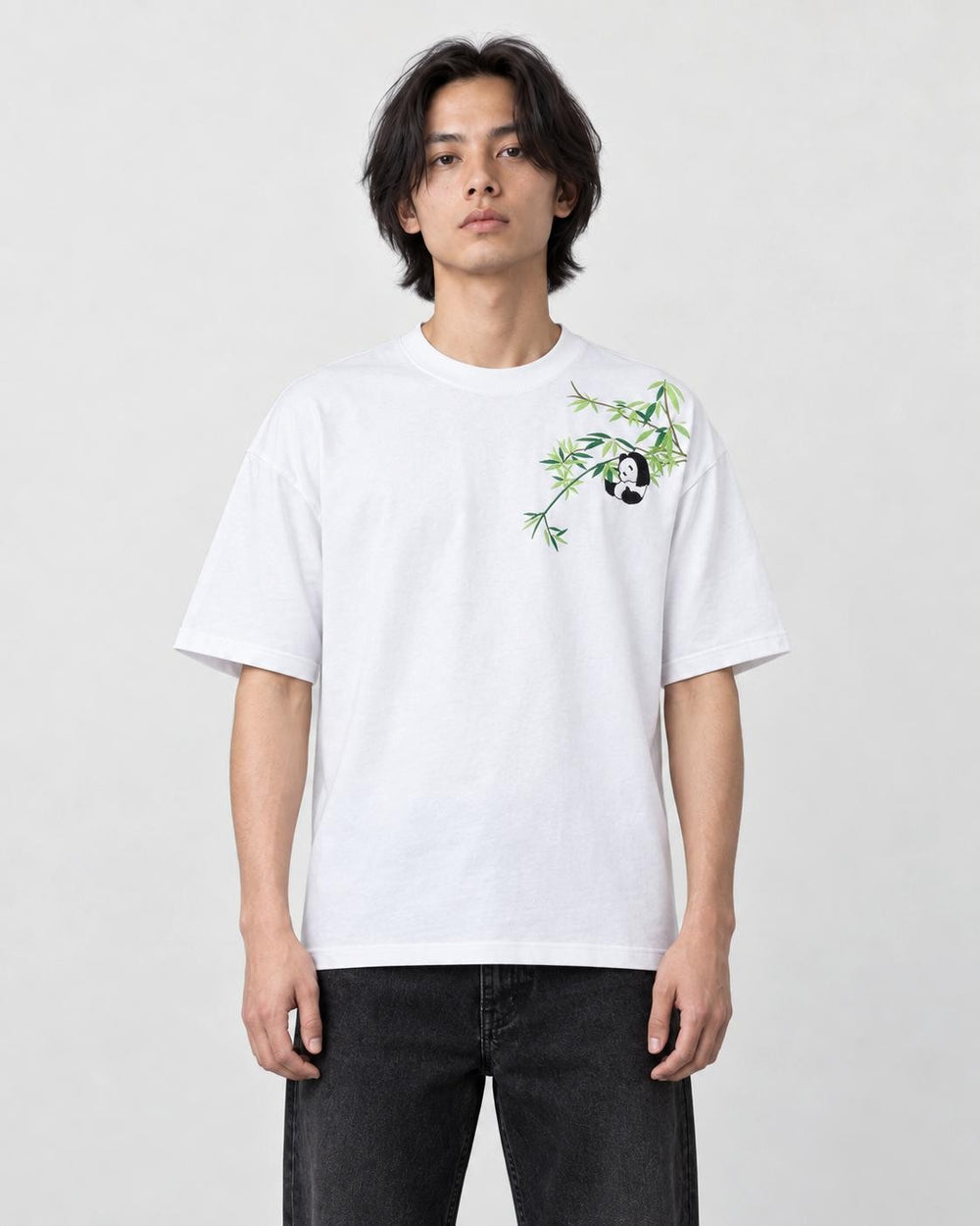 Model wearing the white bamboo and panda embroidered T-shirt with black jeans and white sneakers, front view