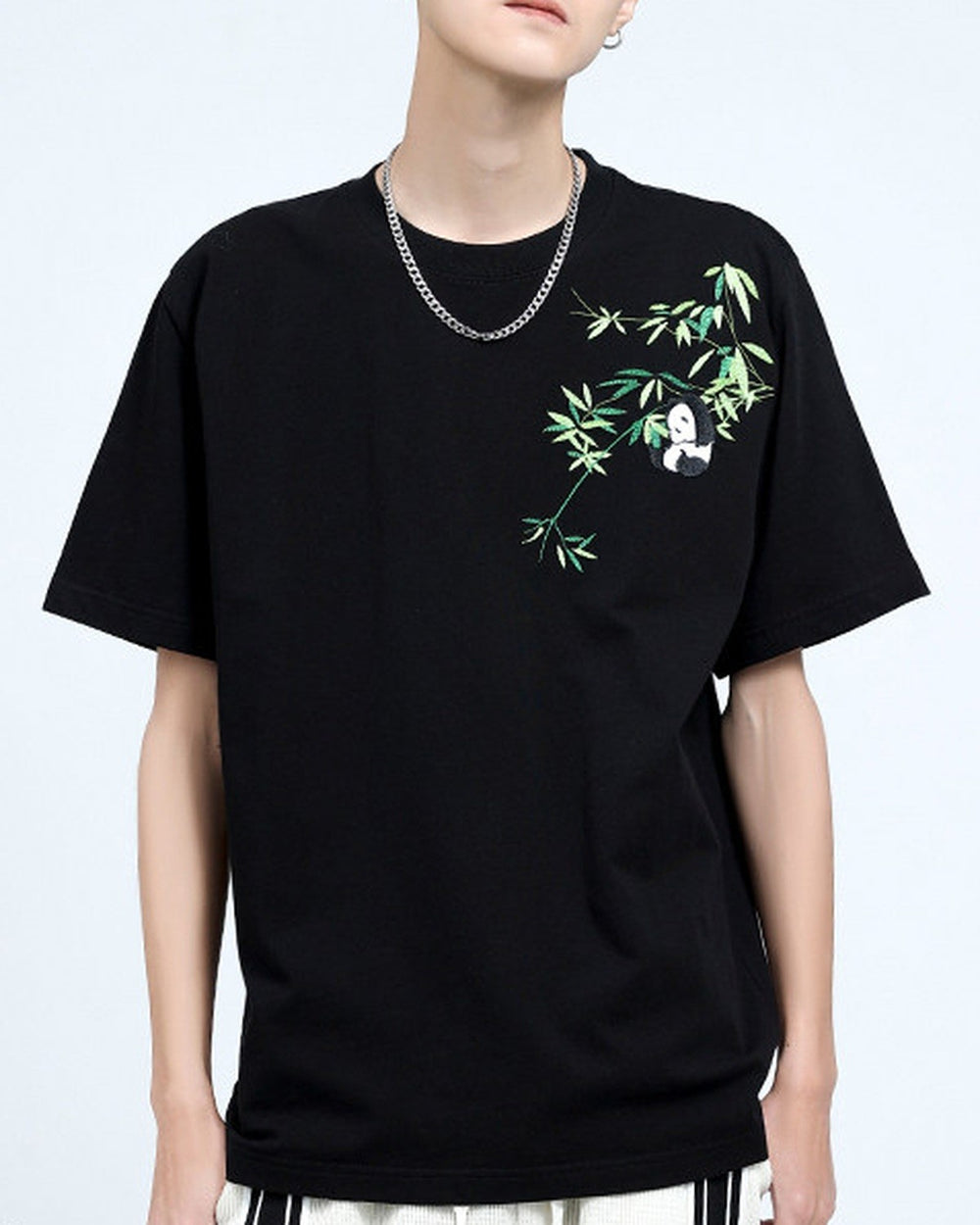 Man in the black embroidered T-shirt, showing the bamboo sprig and panda across the left chest and shoulder