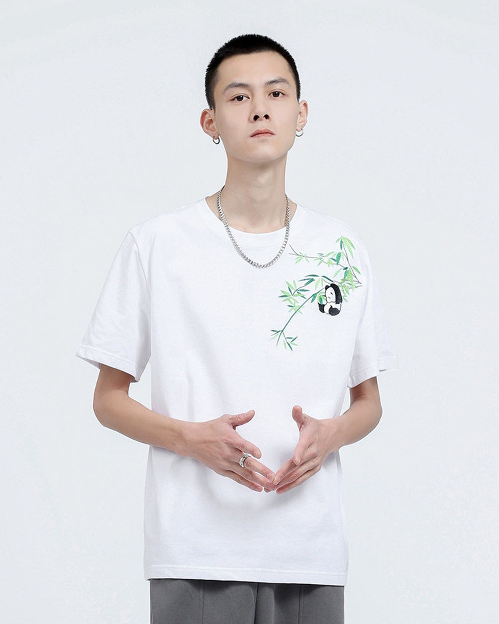 Man in the white embroidered T-shirt, showing the bamboo sprig and panda on the left chest