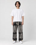Man in banded charcoal tie-dye straight jeans with a white tee and white sneakers, full length