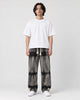 Man in banded charcoal tie-dye straight jeans with a white tee and white sneakers, full length
