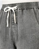 Close-up of the elastic waistband and cream drawcord bow on the washed gray denim joggers