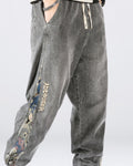 Man in the washed gray denim joggers, showing the woven teddy-bear panel and the ADDRISER lettering down the outer leg