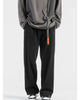 Black corduroy wide-leg pants with a black webbing belt and orange tag, worn with a gray sweatshirt and sneakers