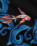 Close-up of the embroidered red and white koi among blue waves on the black fabric