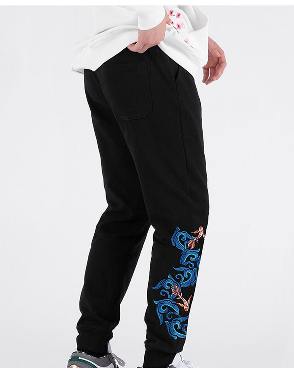 Three-quarter view of the black jogger pants with the koi and wave embroidery