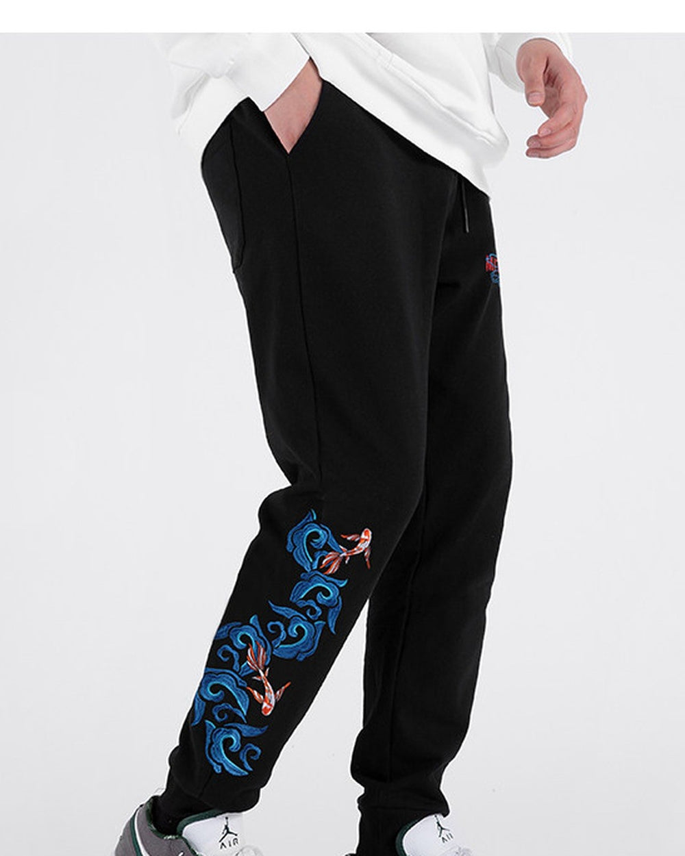Side view of the black jogger pants showing the koi and wave embroidery down the leg