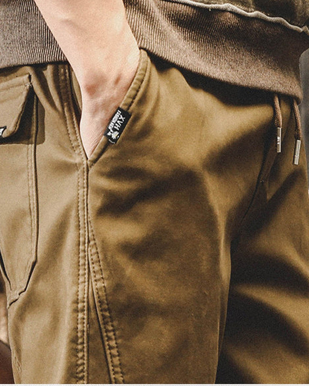 Close-up of the slanted side pocket and drawcord waist on khaki jogger pants