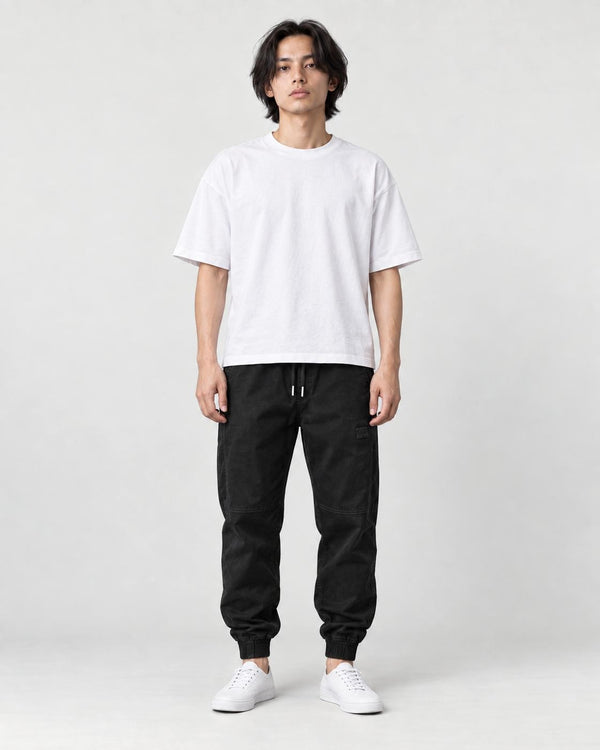 Man in black tapered jogger pants with ribbed cuffs, white tee and white sneakers, full length