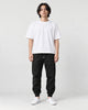 Man in black tapered jogger pants with ribbed cuffs, white tee and white sneakers, full length