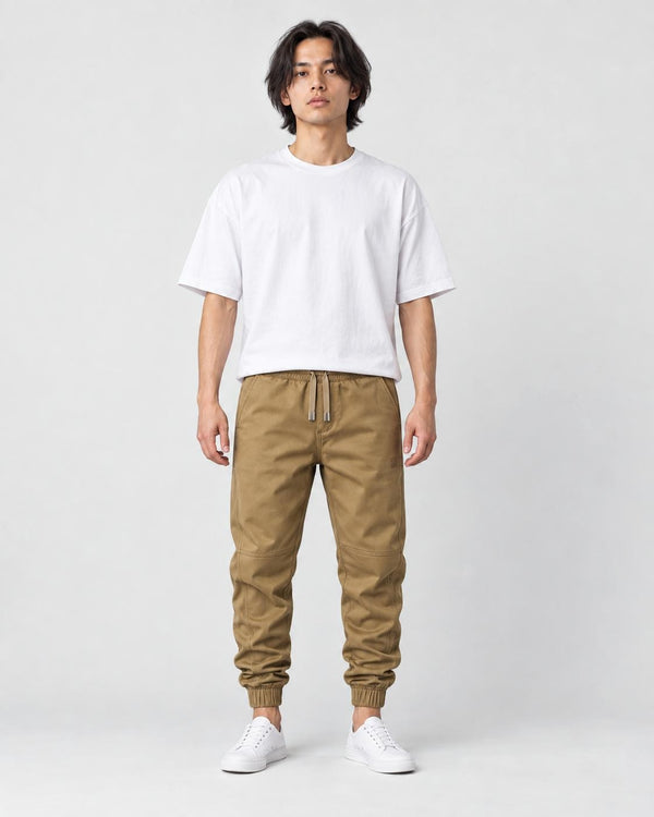 Man in khaki tapered jogger pants with ribbed cuffs, white tee and white sneakers, full length