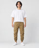 Man in khaki tapered jogger pants with ribbed cuffs, white tee and white sneakers, full length