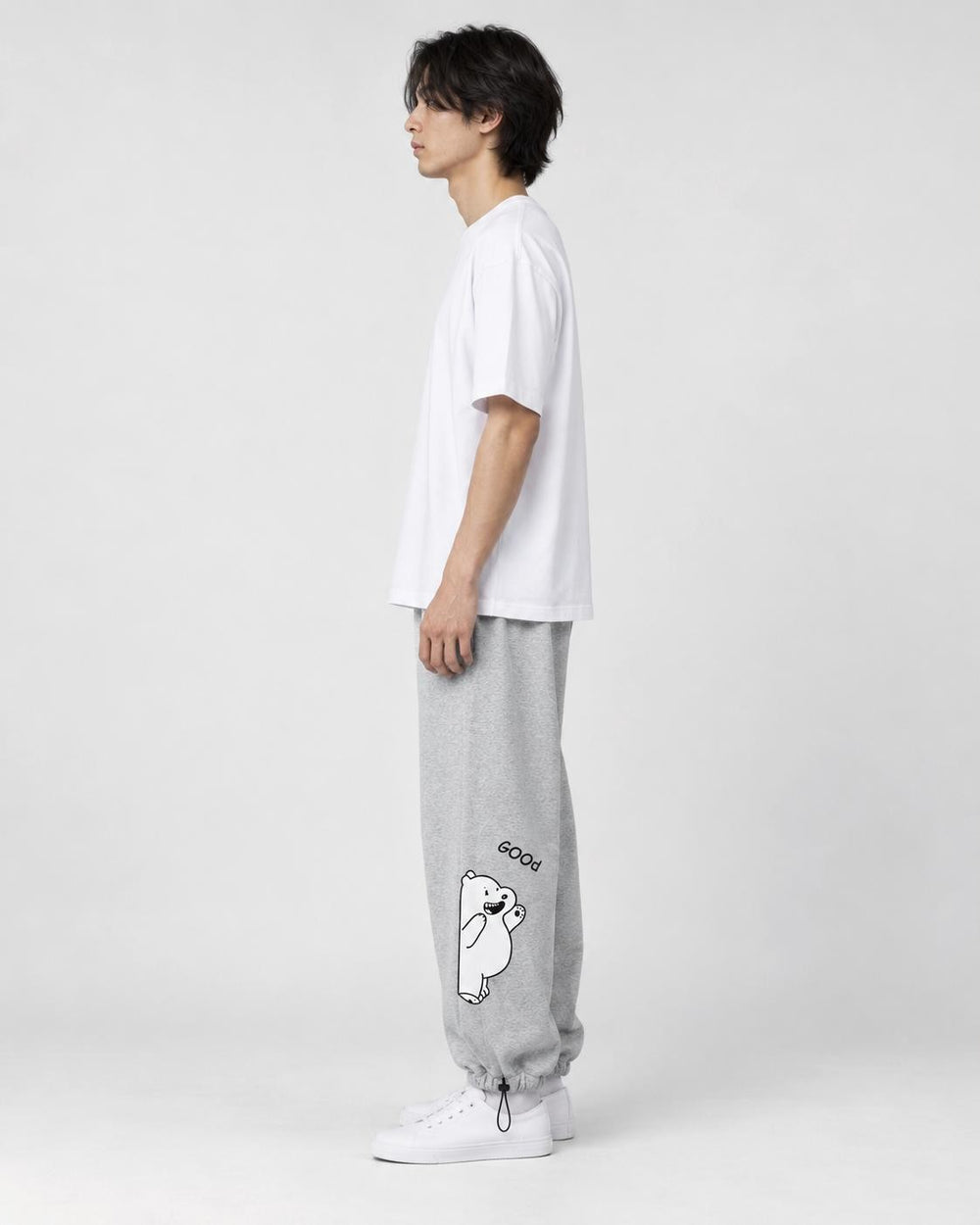 Model seen from the side in the heather gray bear jogger sweatpants with a white tee and white sneakers